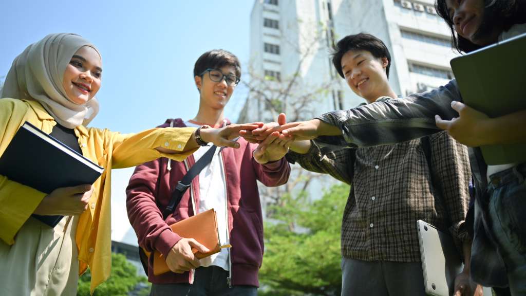 Group of university students joining hand together. Human relati